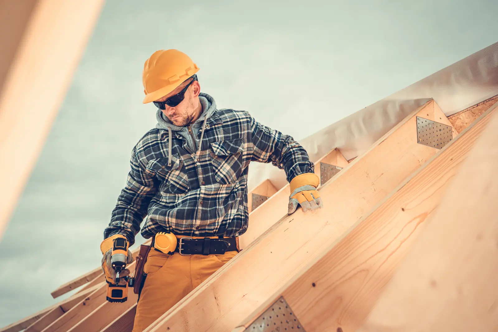 A framer in a hard hat working on roof trusses — hour bank benefits plans track the hours construction workers put in